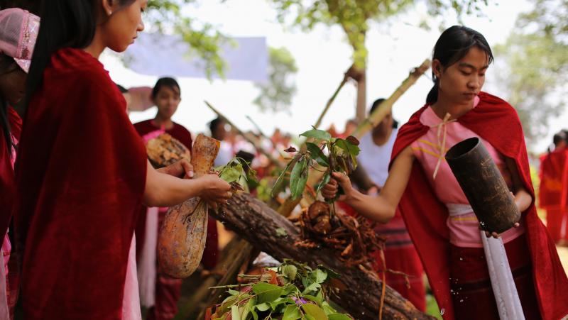 Women bless the log with water and eugenia leaves